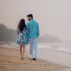 A quiet walk along the shore at dusk. This photo captures a serene, candid moment as the couple walks hand-in-hand, with the gentle waves and misty background creating a romantic atmosphere.