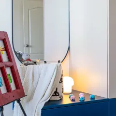 The little details are what complete a design. In this kids' room, the small toys on the dresser and the child's artwork on the easel are not clutter; they are the elements that bring the space to life and make it a real home.