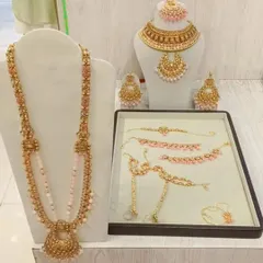 This antique gold and pastel pink bead jewellery set is perfect for a soft, romantic look. It comes with a choker, rani haar, and matching accessories.
