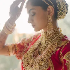 A serene portrait of the bride. The soft, natural light highlights the intricate details of her jewelry and the delicate flowers in her hair, a moment of calm before the ceremony.