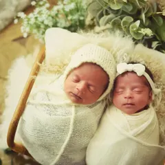 Two little angels sleeping side-by-side. Dressed in neutral cream colors, this portrait highlights the peacefulness and innocence of newborn twins.