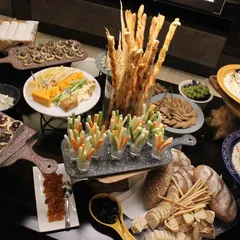 An overhead view of a grazing table we created for a private event. It features an abundant selection of breads, grissini, vegetable crudités, cheese boards, and various dips like hummus.