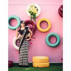 Bold and beautiful. The contrast of the striped saree against the colorful, quirky background of painted tires makes for a fun, modern, and high-impact fashion portrait.