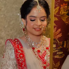 A close-up of the bride's soft glam makeup. The shimmering lids and natural lip color create a look of timeless elegance, perfect for her regal white and red lehenga.