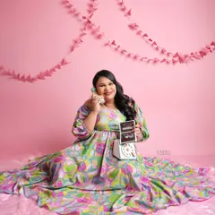 Let's have some fun. This playful, retro-themed shot uses a vibrant pink backdrop and a vintage phone prop for a unique and colorful maternity photo.