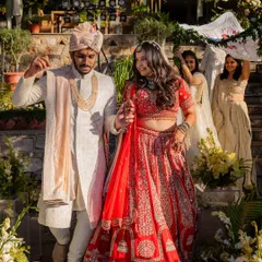 A beautiful shot of the bride's entrance at her destination wedding. Her hair is styled in soft, open waves under her dupatta, a perfect choice for a daytime ceremony.