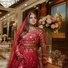 A classic bridal portrait showing the bride in her magnificent red lehenga. We chose a moment of quiet reflection, capturing her elegance and the grandeur of her wedding look before the festivities began.