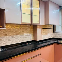 This view of the pink kitchen highlights the fluted glass overhead cabinets, which add texture and a semi-transparent look. The black granite countertop is both durable and stylish.