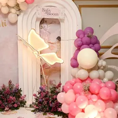 A detail shot of the butterfly-themed stage, focusing on the illuminated butterfly prop and the beautiful balloon clusters in shades of pink, purple, and white.