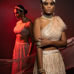 From a high-fashion editorial, this image uses dramatic red backlighting to create a powerful silhouette. I styled this sequined one-shoulder lehenga with a feather detail to blend modern glamour with traditional Indian design.