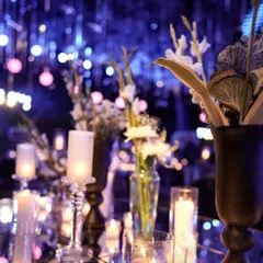 Ambiance is created in the details. This close up shows a beautifully arranged table with an abundance of candles, elegant glassware, and white floral arrangements, all set against a soft, glowing background for an intimate corporate dinner.