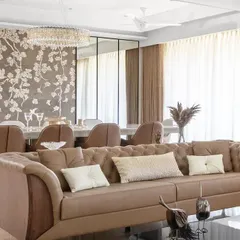 The living area is defined by a tufted leather sofa, set against the backdrop of the dining space and its intricate floral mosaic wall, demonstrating a layered and sophisticated approach to open-plan living.