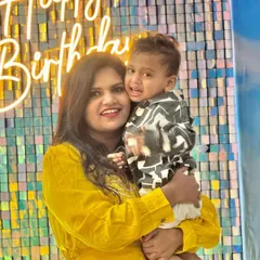 A happy mother and child posing in front of the shimmering backdrop at the Cocomelon-themed party.