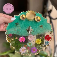 A stunning teal and floral resin pooja thali. The top half is a rich teal, while the bottom half showcases a vibrant array of real flowers, creating a beautiful contrast.
