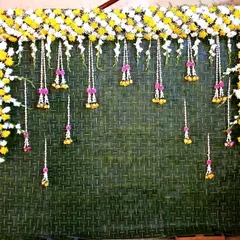 A simple yet elegant backdrop design. We used a woven mat of coconut leaves and decorated it with a border of yellow and white chrysanthemums and delicate hanging floral tassels for a fresh, festive look.