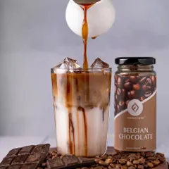A rich espresso shot being poured into a glass of milk for a Belgian Chocolate iced coffee. The contrast between the dark coffee and the white milk creates a visually stunning moment.