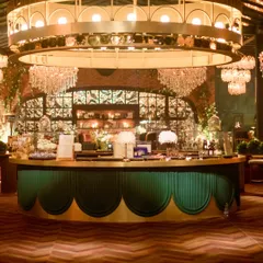 The circular bar was a statement piece at this reception, with a massive custom light fixture that echoed the Art Deco feel of the space. The emerald green and gold palette added a touch of classic glamour.