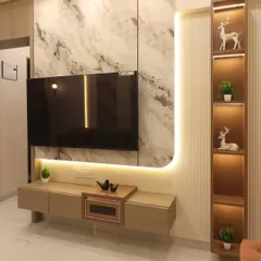 This TV unit in a Bhayandar home combines a marble-finish back panel with fluted wood and integrated shelving. The curved LED strip lighting adds a soft, ambient glow and highlights the different textures used in the design.