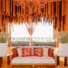 A cozy seating nook inside a tent made entirely of orange marigolds. This immersive design created a warm and vibrant space for a Mehendi in Udaipur.