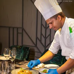 Our chef adds a delicate garnish to a plate of noodles, showcasing the attention to detail that goes into every dish we serve.