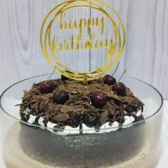 Ready for a birthday celebration, this Black Forest Tres Leches is finished with a golden 'Happy Birthday' topper. It’s a classic flavor combination perfect for any special day.