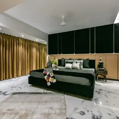 In the heart of this Mumbai home, the master bedroom unfolds like a tapestry of luxury. Indian marble flooring gleams, a metallic backboard reflects dreams, and a custom-made bed beckons with promises of blissful repose.