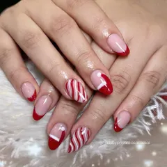 A classic Christmas manicure with red French tips, candy-cane stripes, and cute Santa hat accent nails. It's the perfect festive look.