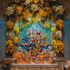 An elaborate and stunning floral decoration for a temple deity. The entire shrine is framed with an abundance of fresh yellow and white flowers, creating a divine look.
