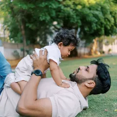 Playful moments like this are the heart of a first birthday shoot. A father lying on the grass, lifting his son up in the air, creating a memory of pure fun.