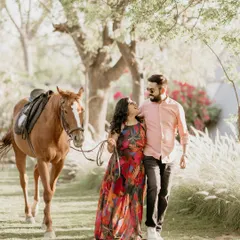 A couple walks hand-in-hand with a horse through a sun-drenched field. This creates a beautiful, rustic, and romantic narrative for their pre-wedding story.