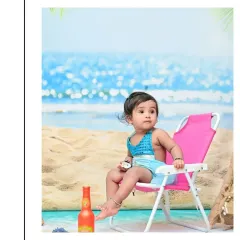 This little beachgoer looks off to the side, taking in the ocean view. The indoor beach setup with a sea backdrop and sand allows for perfect beach photos any time of year.