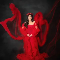 Bold, beautiful, and powerful. This mom-to-be is absolutely radiant in a vibrant red ruffled gown, with flowing fabric creating a dramatic and artistic effect against a dark backdrop.