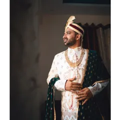A classic portrait of the groom on his wedding day. Dressed in a white and gold sherwani with a velvet shawl, he looks regal and ready for the big moment.