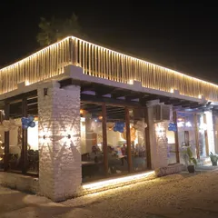 The exterior view of our indoor dining hall at night. The large glass windows offer a great view of the outdoor lawns and pool.