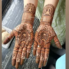A closer look at a symmetrical bridal design, showcasing matching patterns on both hands. The artwork includes lotus figures, peacock motifs, and fine checkerboard patterns for a rich texture.