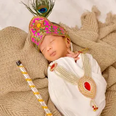A newborn peacefully sleeps dressed as Little Krishna, complete with a tiny flute and peacock feather. This themed shoot combines cultural tradition with the serene innocence of a newborn.