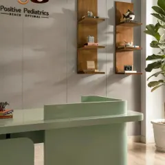 The reception desk was designed with soft, curved edges and finished in a calming mint green to create a welcoming first impression. The wooden display shelves add a touch of warmth and provide space for small, curated objects.