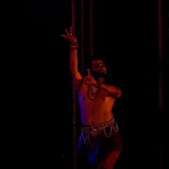A solo portrait of me during a Mayurbhanj Chhau performance, captured under dramatic red and blue lighting.