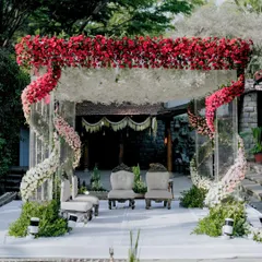 A modern fairytale mandap designed for a romantic ceremony. The structure features a stunning ombre floral arch, transitioning from deep red to soft pink and white, creating a visually spectacular focal point for the couple's vows.
