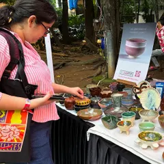 A customer browsing the selection of bowls and jars at my stall during a weekend art festival. It's so rewarding to see people connect with the pieces I've poured my heart into.