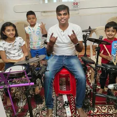 A coach with his young drum students. Using electronic drum kits allows for quiet practice and exploration of different sounds, making it perfect for our group lessons.