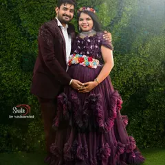 A lovely couple's maternity shoot, with her in a purple ruffle gown and him in a coordinating blazer.