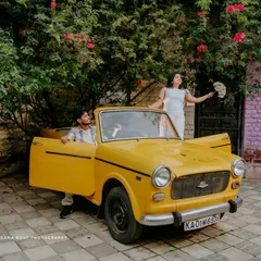 A creative pose with a vintage car, where the mother-to-be stands up in the convertible holding a bouquet. This is a great example of a themed pregnancy shoot.