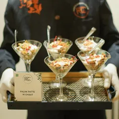 A modern take on a classic street food, our Palak Patte ki Chaat is served in elegant martini glasses. Crispy spinach leaves are topped with yogurt, chutneys, and spices for a delightful bite.