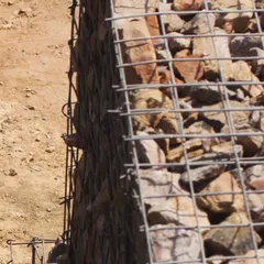 A detail of the gabion wall construction at the Aravali Amphitheatre. This technique uses a simple steel mesh filled with loose rock and stone from the site, creating a strong, porous, and ecologically sensitive retaining wall.