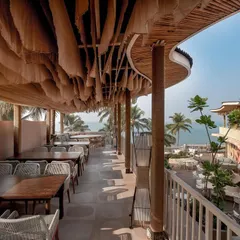 The upper deck at Dubki offers an uninterrupted view of the ocean. The ceiling is a key feature, with draped fabric creating a soft, undulating canopy that mimics the waves below.