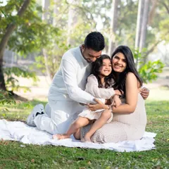 Love grows here. A beautiful family shares a warm hug in a sunlit park during their outdoor maternity session, celebrating the upcoming arrival of their new baby.