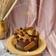 A round Lotus Biscoff and chocolate cake, perfect for an anniversary. The design features Biscoff biscuits, piped chocolate details, and a custom "Happy Anniversary" topper.