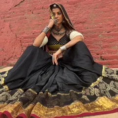 A dramatic and earthy look for Navratri. The black ghagra with a wide gold border is paired with a traditional blouse and heavy silver jewellery, creating a powerful, goddess-like image.