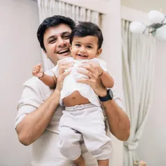 A father joyfully holding his son in their home. One day, this boy will look at this photo and remember this space, this feeling, this exact moment. That's the power of an at-home photography session.